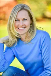 A woman in blue shirt sitting on grass.