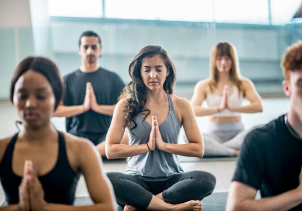 A group of people sitting in the middle of a yoga class.